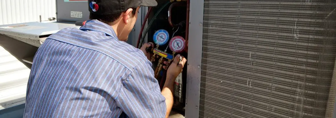 HVAC technician servicing a condenser unit in Decatur